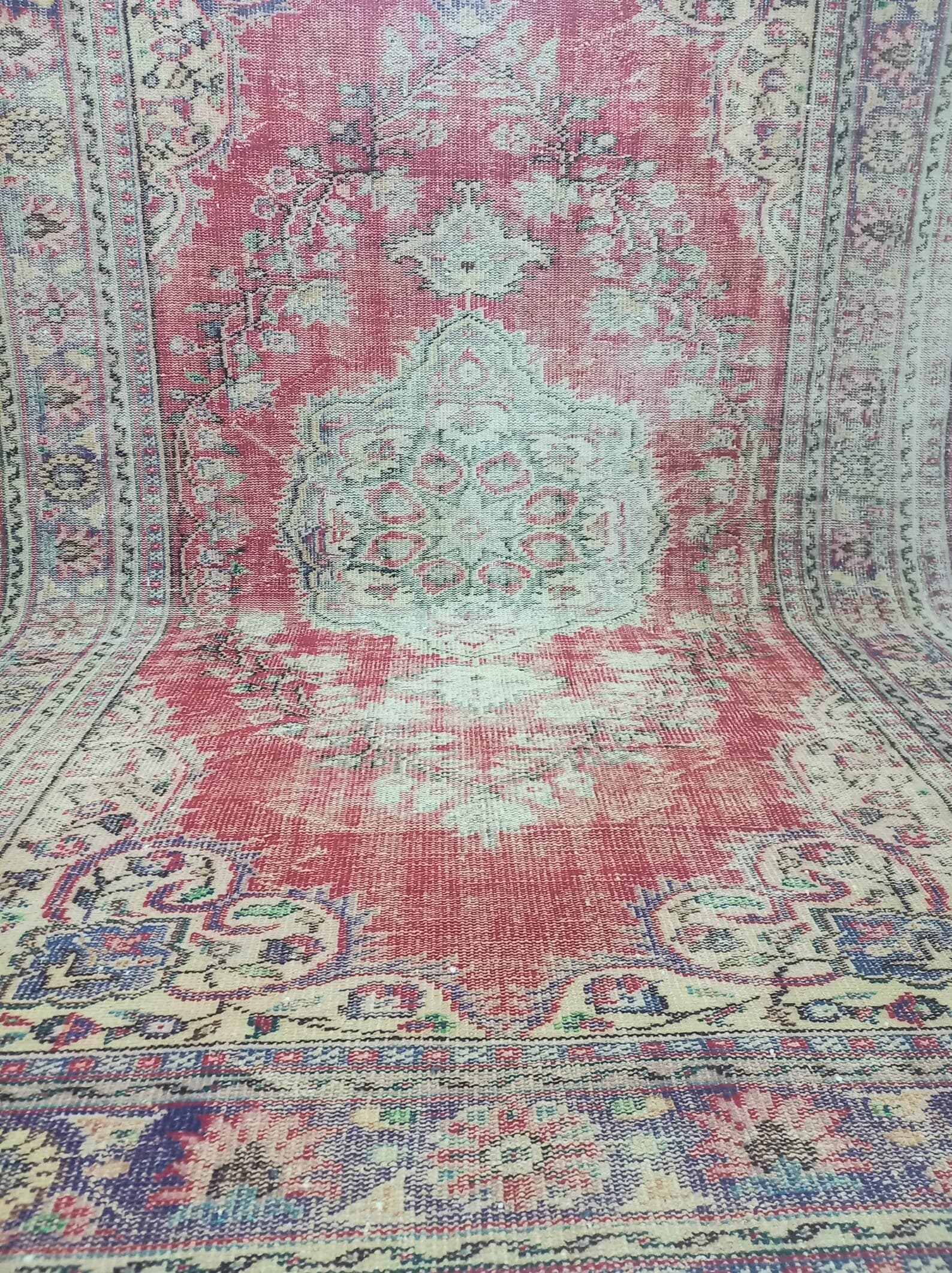 Close view across the low, time-worn pile of a red vintage Oushak rug.